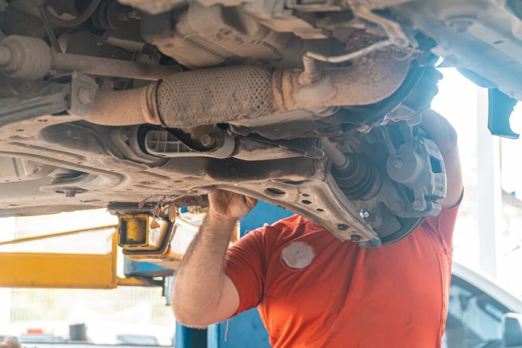 Mechanic checking a commercial truck's suspension bushing underneath the vehicle